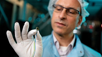 Projektleiter Harald Schenk, der einen Mikrochip in seiner Hand hält