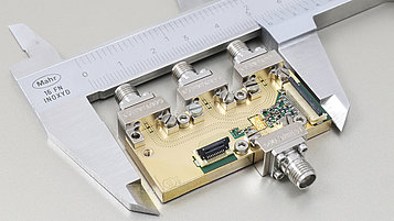 The picture shows a digital GaN-based transceiver module in a caliper. 