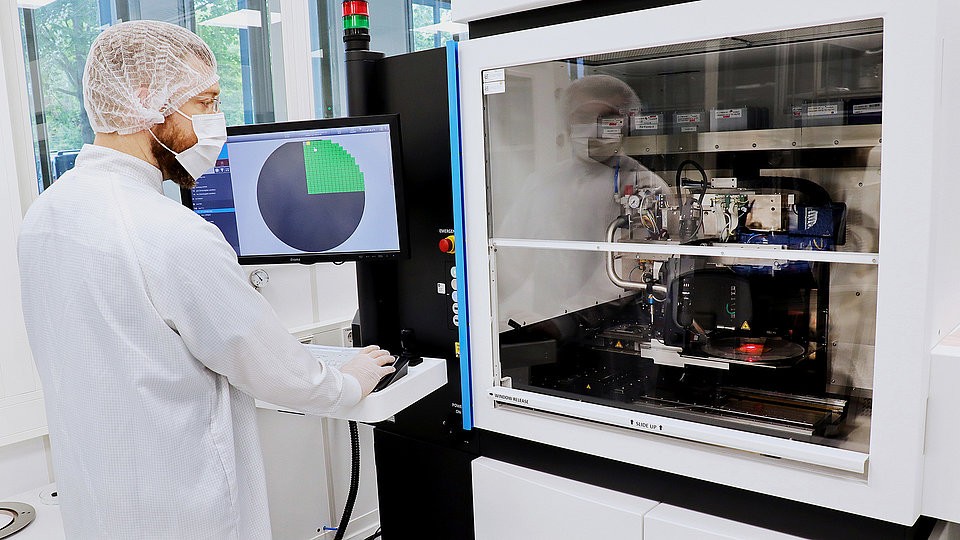 The photo shows a male technician in a lab coat using a die bonding machine. 